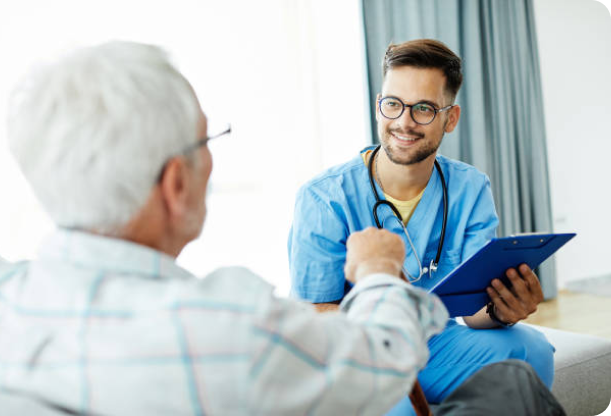 A healthcare professional smiling at an elderly man during a conversation.