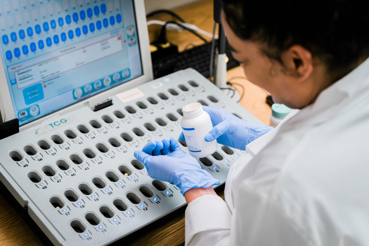 Photo of a young female pharmacist working in a pharmacy setting, busy at work and smiling