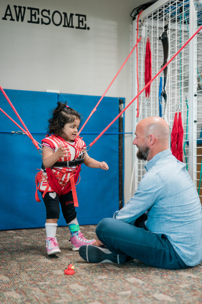 Image of a young female child in equipment who is working with a male physical therapist