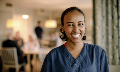 Smiling woman in blue scrubs in a social indoor setting.