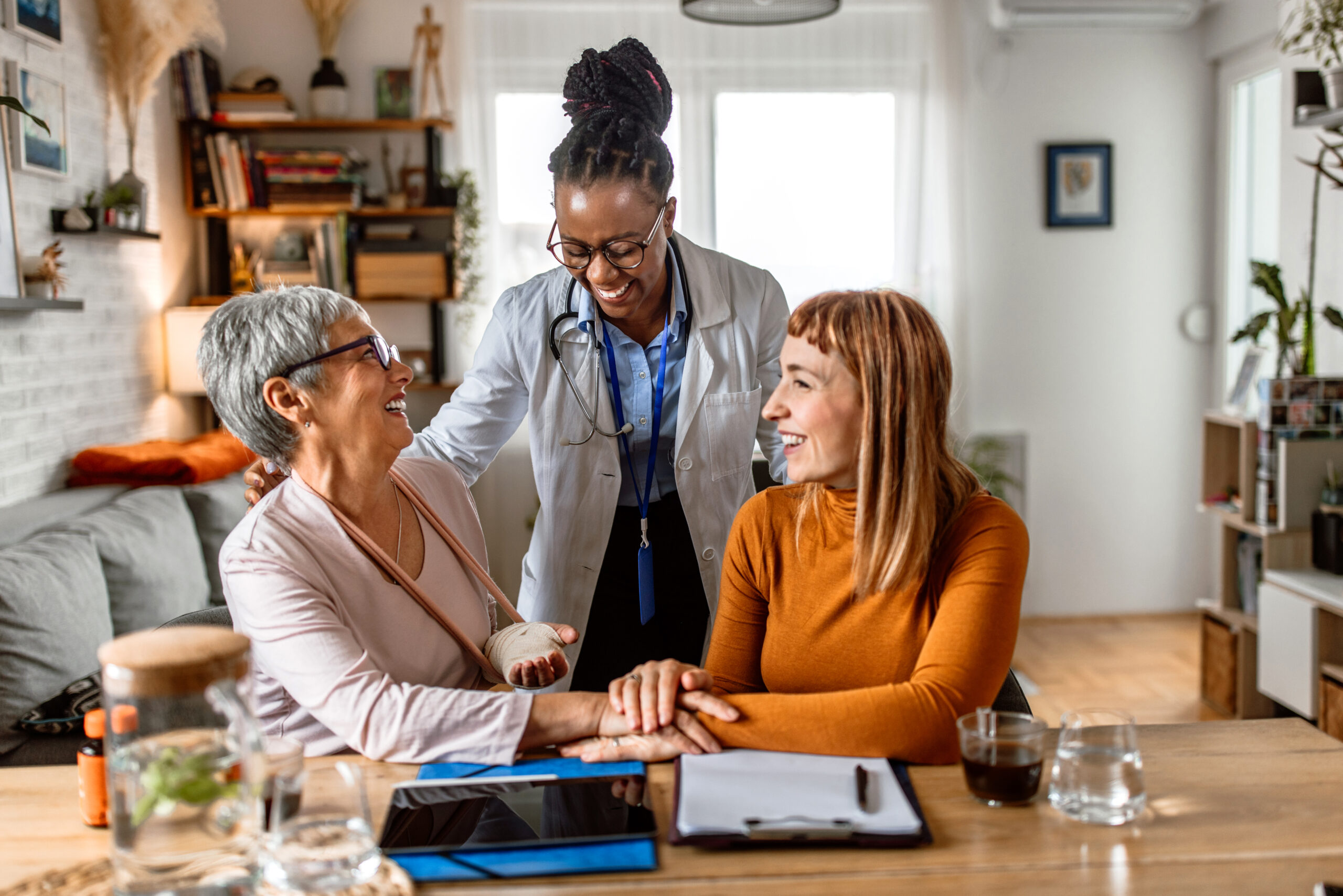 Doctor home visit - image of 3 women, one doctor, elderly patient, and patient's daughter during a home health doctor visit