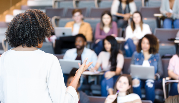 Lecturer addressing students in a classroom.