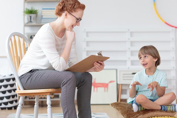 A young boy and a woman with a clipboard talking and smiling