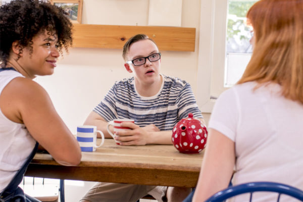 Young man with IDD listens intently to a woman speaking to him